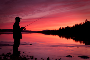 Silhouette of man fishing at sunset